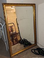 Full view of the rectangular mirror leaning against a wall, showing its overall size, frame design and some reflections.