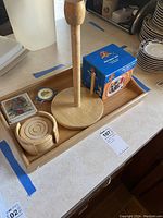 Wooden serving tray displaying paper towel holder, round wood coasters in holder, tea bag dish, cardinal bird coasters, and boxed Looney Tunes Hot Spot mug set.