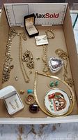 Overview of all costume jewelry items in the lot inside a cardboard box