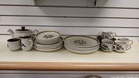 Full set displayed on shelf including teapot, creamer, sugar bowl, cups with saucers, and tea, salad, dinner plates