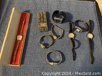 Full overview of all 9 vintage ladies watches laid out on a blue fabric surface showing the variety of watch types and bands including boxed watch, stretch bands, leather and rubber straps.