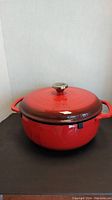 Front and side view of the red enamel Lodge Dutch oven with lid, showing the overall shape and condition.