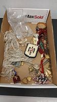 Box containing assorted vintage costume jewelry including shoe clips, necklaces, and earrings