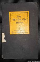Front cover of the book showing the yellow label with title and author's name, black cloth cover with some wear and a torn area near spine.