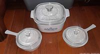 Three Corning Ware pieces arranged side by side showing shape, lids, and cornflower blue patterns.