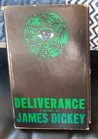 Front cover of the dust jacket featuring green circular motif with an eye and text 'Deliverance A Novel by James Dickey'