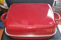 Closed large rectangular red enamel roaster with handles on each side. Glossy finish with no visible chips or major wear.