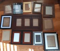 Image showing all 12 assorted picture frames laid out on wood floor, varying sizes and styles.