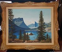 Front view of the painting showing a mountain and lake scene with pine trees and a person in a small boat. The frame is ornate with gold color and intricate floral corner details.