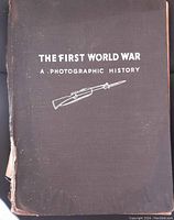 Front cover of the book showing black cloth with white text and rifle illustration, showing wear and edge damage.