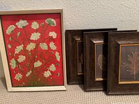 Set of four botanical art pieces. One original painting by Mabel Koser of white flowers on red background, framed. Three smaller framed botanical leaf artworks with dark frames and gold mats.