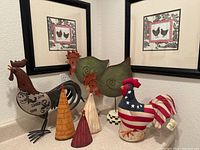 Full view of chicken-themed decor on a countertop including metal rooster, metal hens, wooden cone chickens, patriotic rooster, and two framed prints on the wall