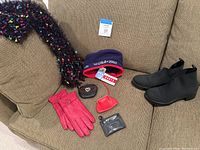 Photo showing multicolor fuzzy scarf, two hats, four small coin pouches and red gloves on a beige couch.