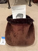 Brown shiatsu foot massager with soft plush fabric, showing user manual on top.