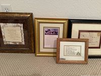 Four framed quotes displayed leaning against a wall on carpet, showing various frame styles and quote layouts.