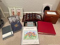 Overview of photo frames, albums, Moleskine journal, and keepsake box arranged on floor showing variety and condition