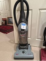 Full view of Hoover Sprint bagless upright vacuum cleaner showing hose, handle, and base.