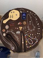 Full overview of lot items on brown surface including jewelry pieces, hand mirror, hair combs, and ring box