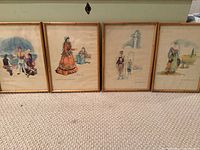Four framed prints lined up on a carpeted floor showing traditional Lebanese cultural scenes.