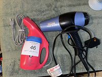 Photo showing a pink handheld clothing steamer and a black and blue BOTTI 1875 hair dryer with cords, on a grey cloth surface.