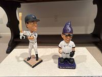 Two Colorado Rockies bobbleheads on display showing details of player uniforms and accessories