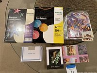 Photo showing two unopened packages of cardstock - Wausau Stardust Premium and Exact Vellum Bristol Cardstock - along with assorted small cards and a sealed package of stickers.