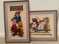 Both framed needlepoint pieces together showing teddy bears theme and framing style.