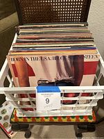 Full crate of vinyl records showing the top album 'Born in the U.S.A.' by Bruce Springsteen and overall quantity.