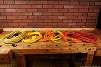 Six coils of extension cords arranged side by side on workbench