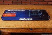 Boxed Mastercraft Workstation Shop Stand with blue and black packaging, showing product image and description.