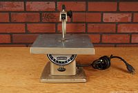 Front view of Craftsman bench top jig saw showing angle adjustment gauge on table surface and power cord coiled beside base.