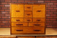 Front view of entire cabinet showing eight drawers and two top doors with birdseye maple fronts and walnut handles