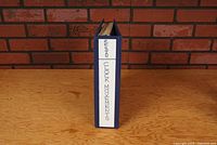 Front view of blue 3-ring binder with white label handwritten: 'RE: SWAN CLOCK MOVEMENTS'.