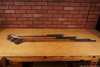 Full length view of 6 golf clubs showing wooden shafts and metal/wood heads