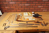Overview of the entire lot showing a variety of metal, brass and wooden measuring tools including rulers, vernier calipers, and dividers.