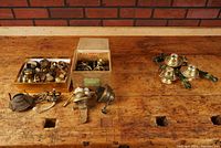 Wide shot with two open boxes and some loose parts on wood surface showing brass oil lamp burners and parts