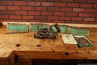 Wide view of plane, cutter boxes, instruction manual, and accessories on workbench