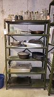 Full shelving unit showing multiple metal shelves with various glass jars, bottles, pans, pots and trays.