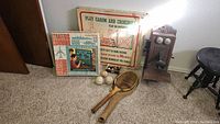 Full view showing antique wall phone, two boxed board games, three balls, and wooden Spalding racquet lying on the floor.