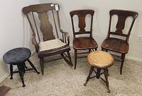 Set of five antique wooden furniture pieces: rocking chair, two side chairs, two piano stools, arranged on carpet against wall