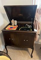 Front-angle view of dark wood console with hinged lid open showing turntable, reproducer and tonearm