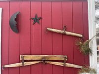 Photo of red exterior wall with rustic wooden yoke, wooden pole, metal star and crescent moon decorations
