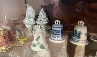 Photo showing a variety of porcelain and glass bells including Santa Claus figurine, Christmas tree, and porcelain commemorative bells for 1977 and 1978 Christmas.