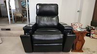 Black leather electric armchair viewed from front, showing padded cushions and armrests.