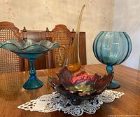 Overview photo showing all four pieces of MCM art glass on a wooden table with a doily underneath.