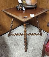 Full view of the square top and spiral spindle legs with stretcher base on carpeted floor.