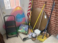 Wide shot showing all items in the lot including step stool, bodyboards, brooms, bucket, gloves, and table leaning against wall