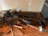 Overview of hand saws, garden shears, hand drills, metal box, and horn on wooden table