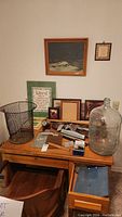 Table top with vintage office supplies, frames, metal wastebasket, large glass jug