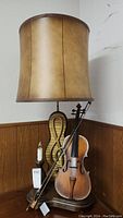Full view of the violin table lamp with bow, musical backdrop, and brown shade.